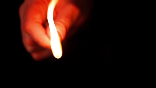 A man lights a match on a large matchbox.