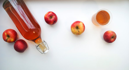 Top view of a bottle and glass with natural apple juice on white, banner. Homemade apple juice.