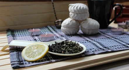 Fototapeta na wymiar dry green tea, a slice of lemon, marshmallows and items for tea in the cozy kitchen
