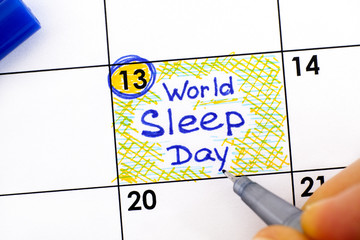 Woman fingers with pen writing reminder World Sleep Day in calendar.