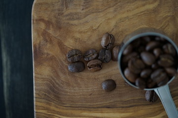 Kaffeebohnen in einem Kaffeedosierlöffel auf einem Holzbrett