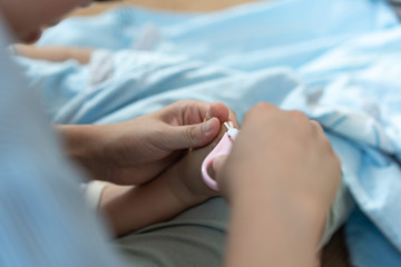 The mother took the scissors and cut the toenails for the child