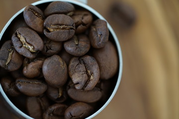 Kaffeebohnen in einem Kaffeedosierlöffel auf einem Holzbrett