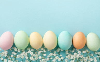 Pastel Easter eggs on blue background top view. Flat lay style.