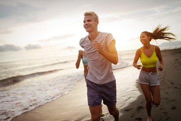 Fototapeta premium Group of friends running at the beach on beautiful summer sunset