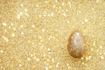 Golden Easter Egg on blured golden background. Easter celebration concept. Top view, copy space