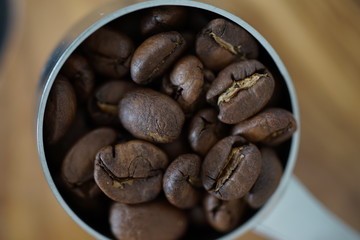 Kaffeebohnen in einem Kaffeedosierlöffel auf einem Holzbrett