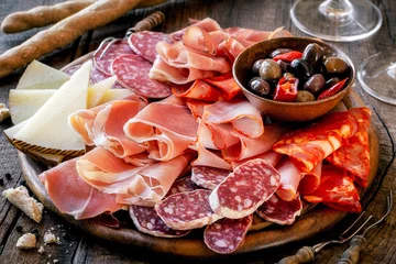 Fotobehang Cures meat platter with cheese and spicy olives served as traditional Spanish tapas on a wooden board. Selection of ham, salami and goat cheese © kuvona
