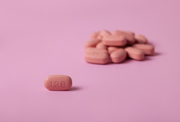 HIV/AIDS therapy pills on pink background.