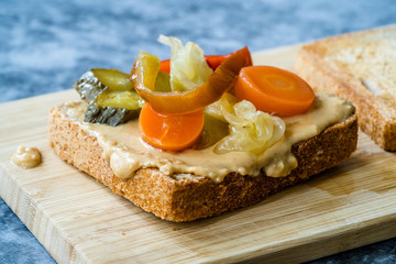 Organic Healthy Homemade Peanut Butter and Pickle Sandwich on Wooden Board.