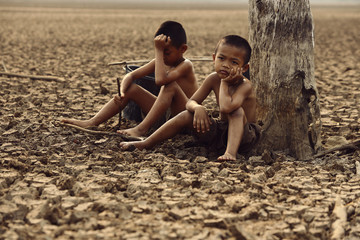 The boy sat on a parched ground due to water shortage due to global warming. Global warming and climate change concept