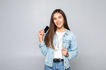 Portrait of a smiling young woman holding credit card isolated over white background