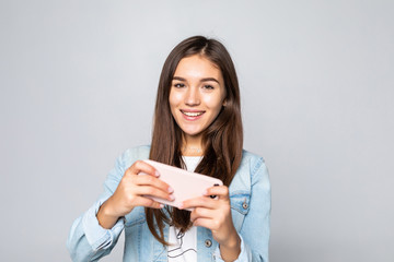 Young woman playing games in her cell phone isolated over a white background