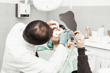 A young male dentist doctor treats a patient. Medical manipulations in dentistry, surgery. The...