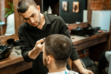 Haircut at the hairdresser. Barber cuts the hair on the client's head. The process of creating...