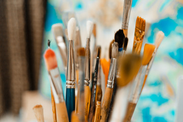 Fototapeta premium Tools and equipment for the artist. Palette and brushes close-up. The process of drawing and creativity. The picture is in blue.