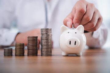 businessman hand putting coins with piggy bank.money saving and investment concept.