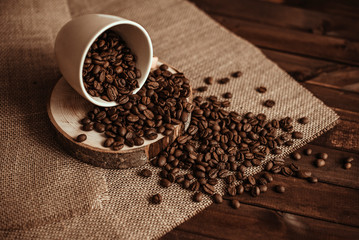 Coffee cup with coffee beans on burlap on a wooden background. Roasted natural coffee
