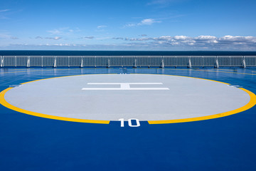 Helicopter landing site helipad helideck of a big ship boat tanker with white railing, ocean water, skyline and blue sky in background - concept transport sea travel copter flight maritime aviation