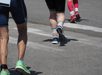 Lower body parts of running men and women in jogging shoes