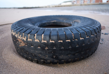 rubber dirty old vehicle tyre washed up on a sandy luxurious beach destination. Environmental plastic pollution issue causing world  news. Health disaster on beaches.