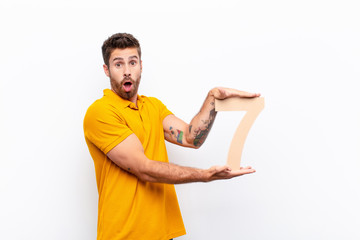 young handsome man surprised, shocked, amazed, holding a number 7.