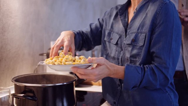 Slow motion shot of woman holding a plate with tortellini in kitchen