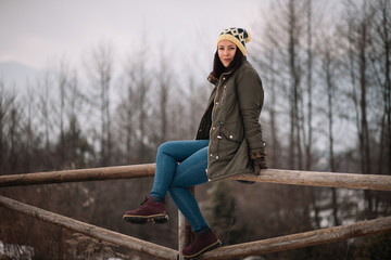 Fototapeta premium Young woman on wooden fence in the forest