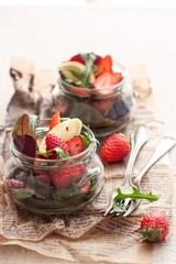 Fresh salad with strawberries and arugula in a glass jar