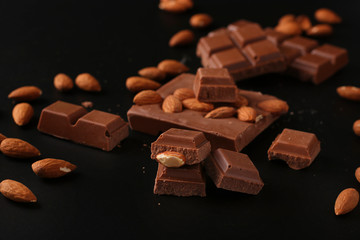 Chocolate with almonds and cinnamon on a dark background