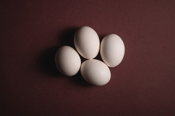 Four white eggs on brown paper background, top view, happy Easter day