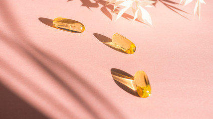 Liquid gelatin capsules with flower shadow on pink background