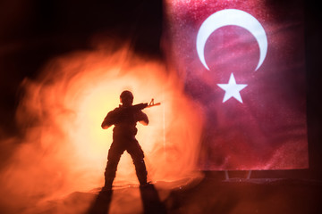 Silhouette of soldier with rifle against a turkish flag. Selective focus