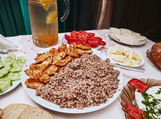Georgian breakfast close up detail of fresh tomatoes, fried cooked bulgur and fried chicken strips