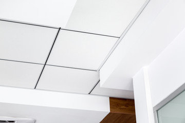 multi-level ceiling with three-dimensional protrusions and a suspended tiled ceiling white color,...