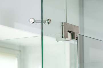 Iron hinges of a glass door on bathroom at the corner junction of a glass construction, close up.