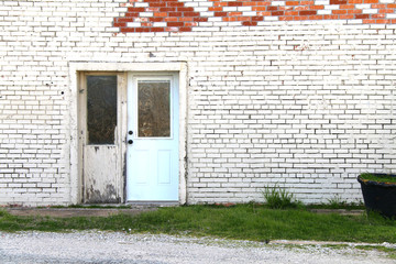 an abandoned painted white brick store doorway with exposed red brick