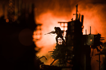 Army sniper with large caliber rifle standing in the fire and smoke. War Concept. Battle scene on...