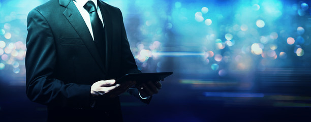 Businessman using a tablet computer on a shiny blue background