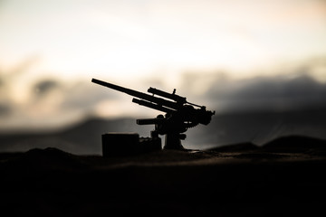 An anti-aircraft cannon and Military silhouettes fighting scene on war fog sky background, World War Soldiers Silhouettes Below Cloudy Skyline at sunset. Attack scene. Armored vehicles.