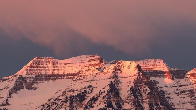 Snow storm moving over mountain peaks during sunrise over Mount Timpanogos in Utah.