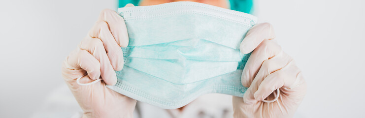 Doctor holding medical face mask in hands.