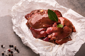 Raw chicken livers on a paper on stony countertop. Poultry, giblets.