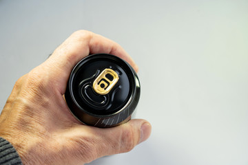 The elderly man holds an aluminum can of black color on a white background
