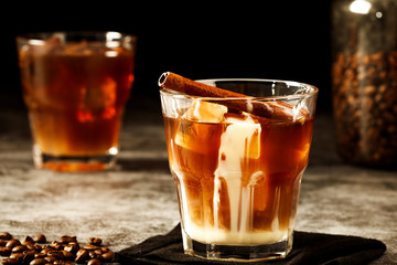 Iced coffee with milk on a dark background. Coffee with ice and cream on a gray background close-up.