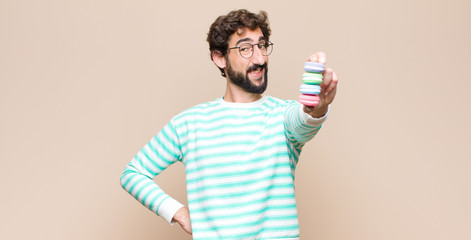 young man with macaroons against flat wall