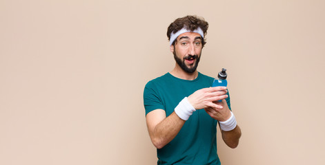 young sports man with an energy drink bottle against flat wall