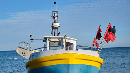 Blue-yellow fishing boat next to sea. © Szczym