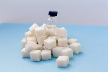 Sugar addiction, insulin resistance, unhealthy diet, sugar cubes and bottles of insulin on blue...