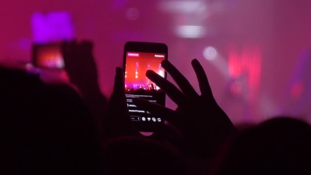 People at the concert shoot videos on their mobile phones. Slow-motion recording of the concert.